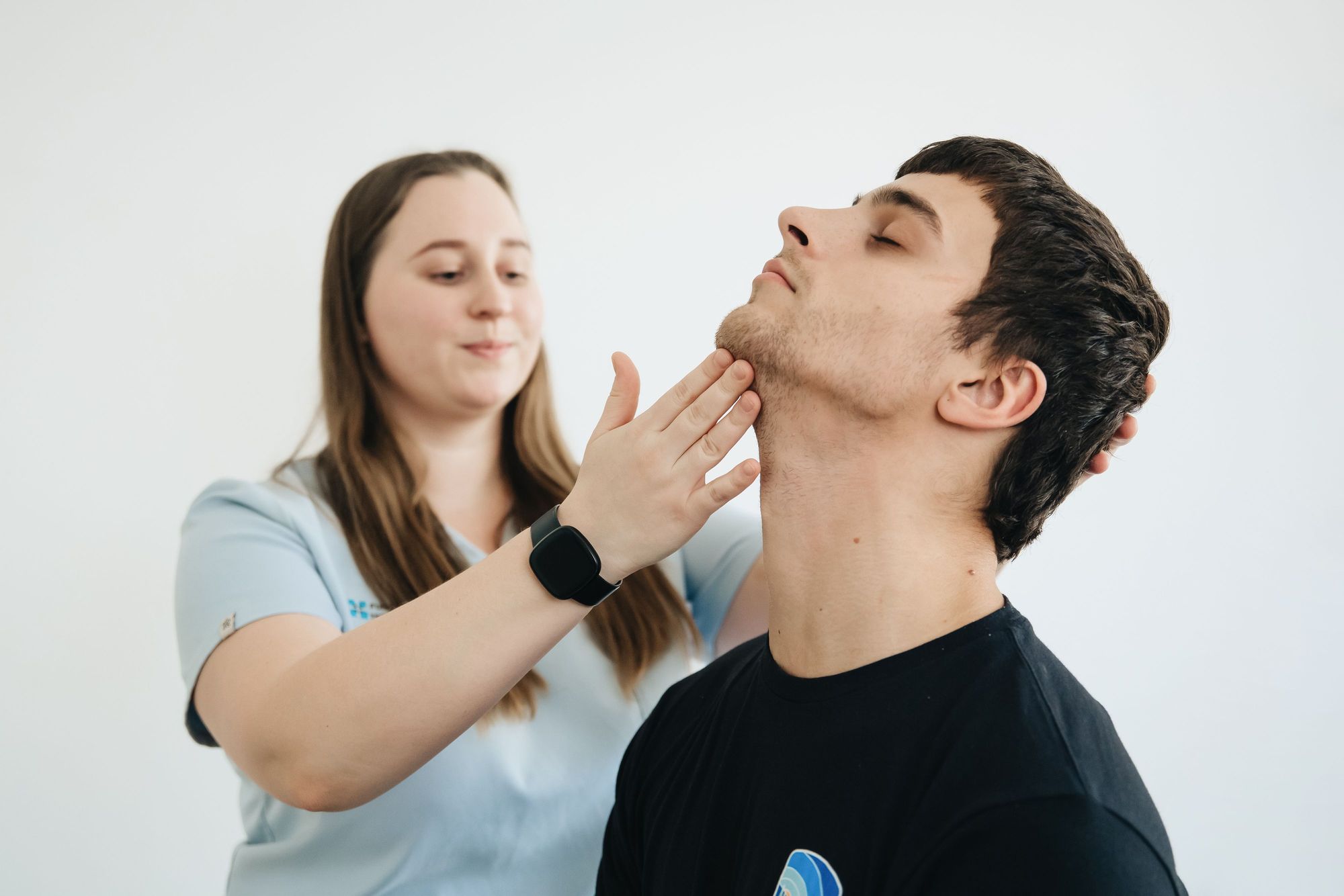 Physical therapist treating a male patient's neck in clinic