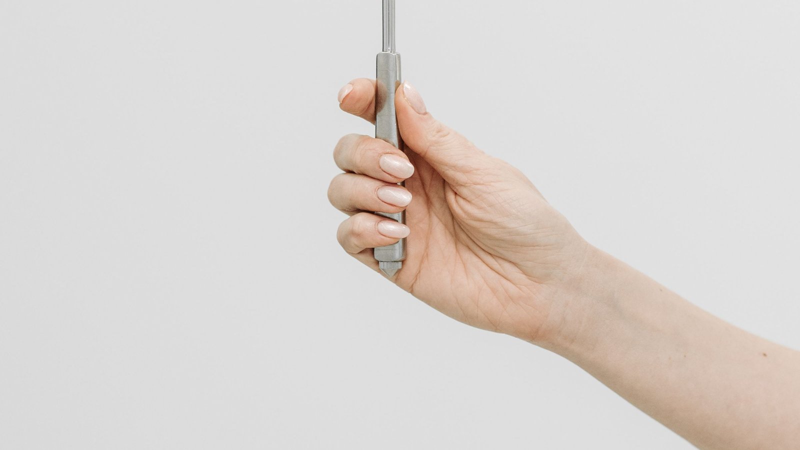 A hand holding a reflex hammer against a light background